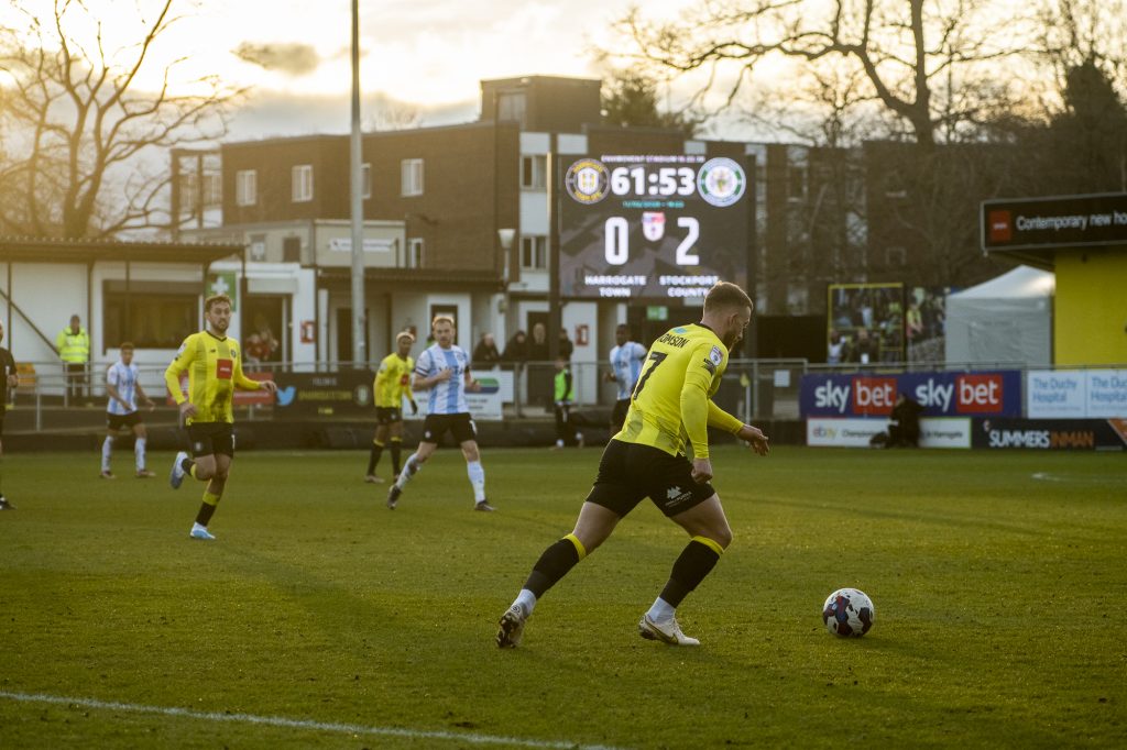 Footballers on pitch with LED screen with scores